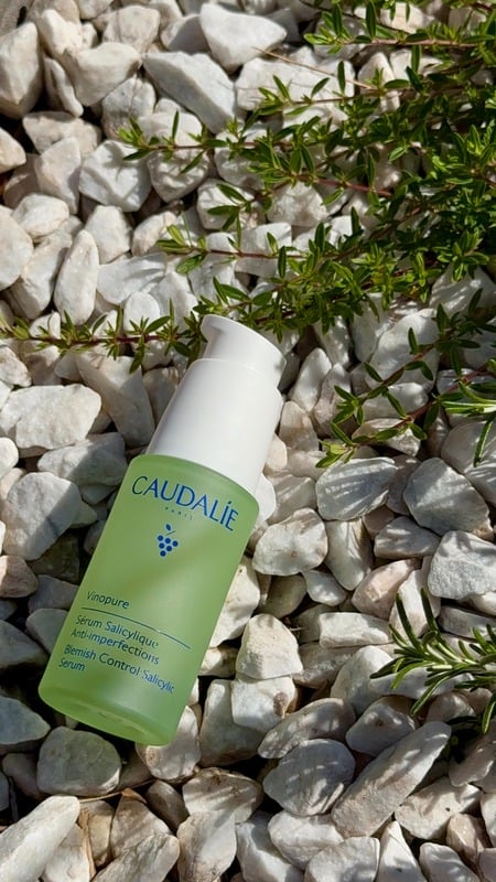 Sérum Caudalie Vinopure posé sur des galets blancs